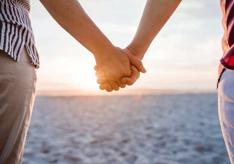 A close up of a couple holding hands against the light of the setting sun. This could represent cultivating relationship fulfillment in Ontario, CA. Learn more about what goes into a fulfilling relationship in Ontario, CA by contacting an online therapist in ontario, CA today.